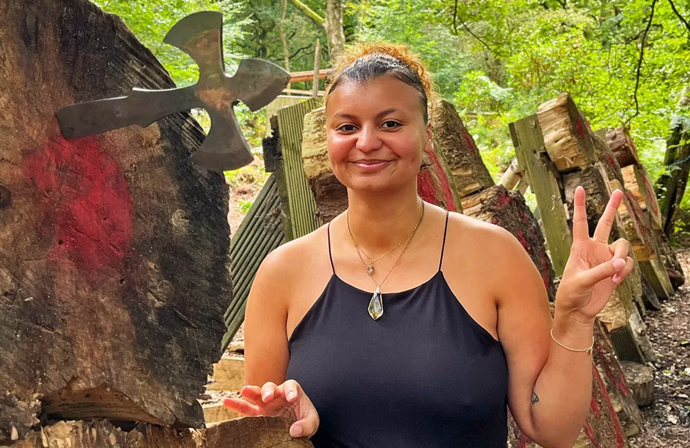 Smiling happy girl with a knife throwing angel and wooden target at Adventure Now Manchester