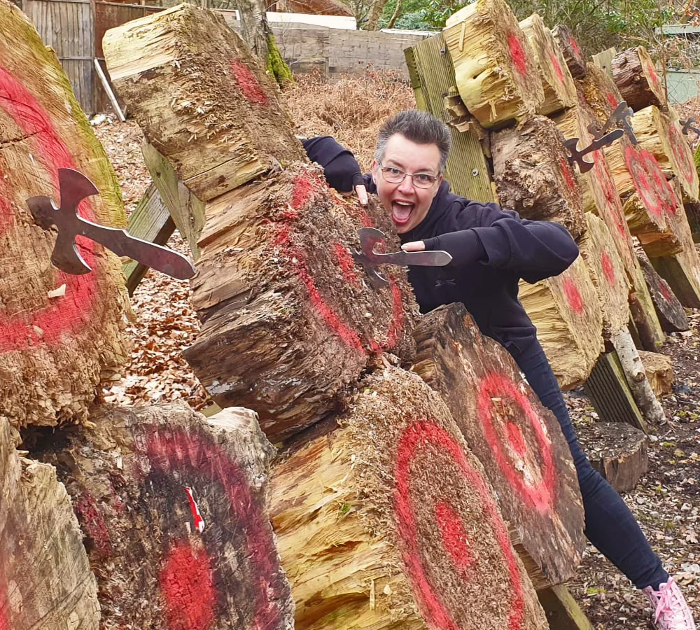 Excited lady on large throwing range with two throwing knives stuck in two targets