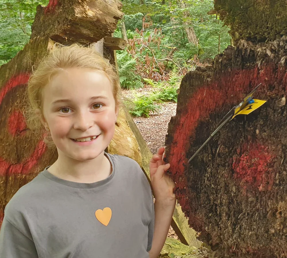 Happy child next to a throwing knife stuck into a target