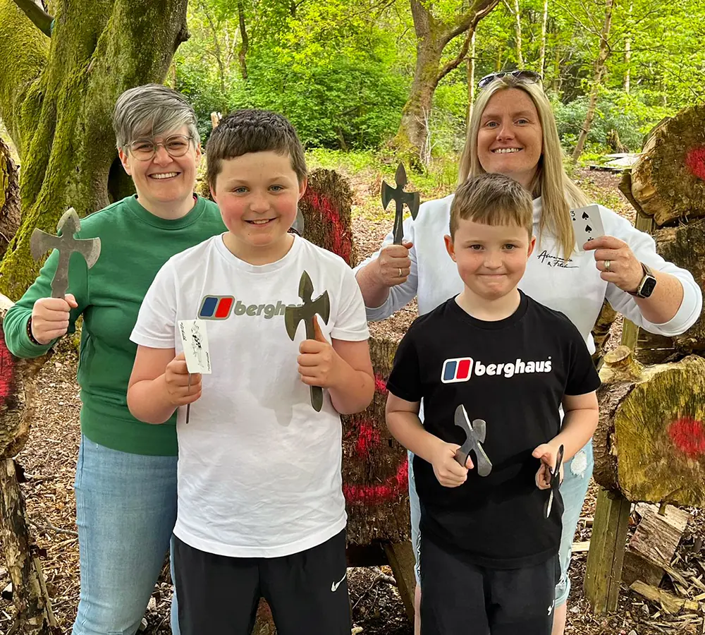 Family group stood in front of knife targets whilst holding throwing angels