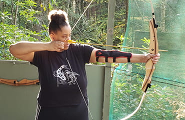 Lady firing arrow at Archery Club at Adventure Now Manchester