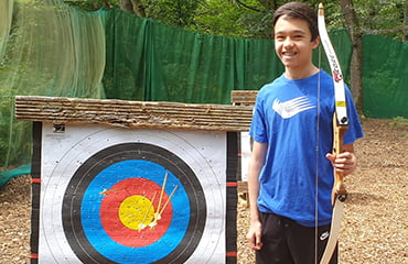 Junior posing with target at Archery Club at Adventure Now Manchester