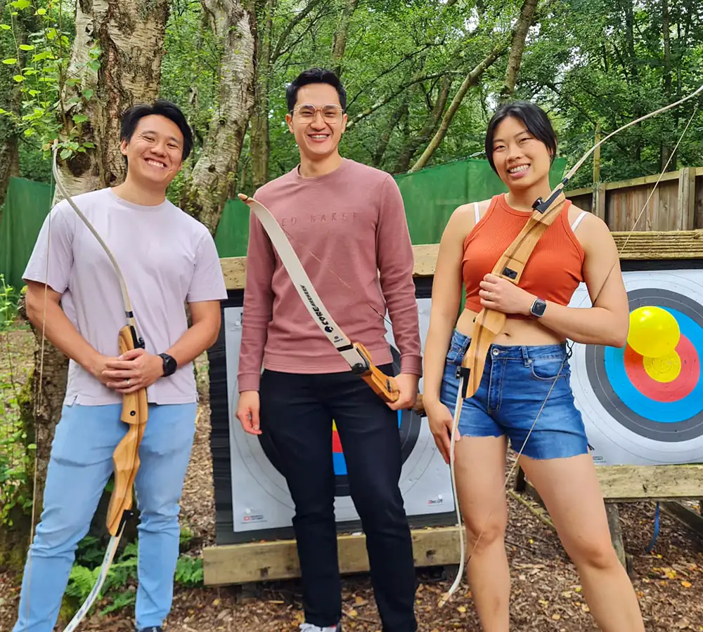 Group of friends standing in front of archery targets with bows in their hands