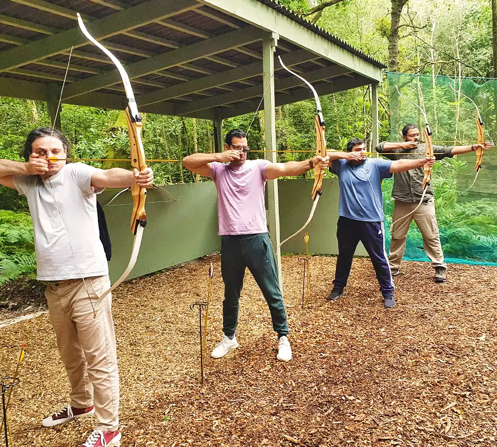 Four men trying archery outdoors at Adventure Now in Manchester