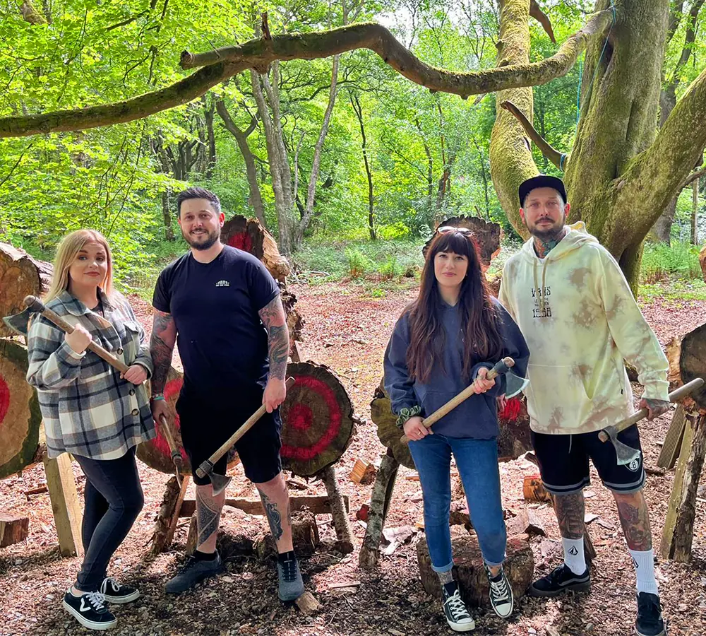 Two happy, smiling couples posing with throwing axes in front of axe targets