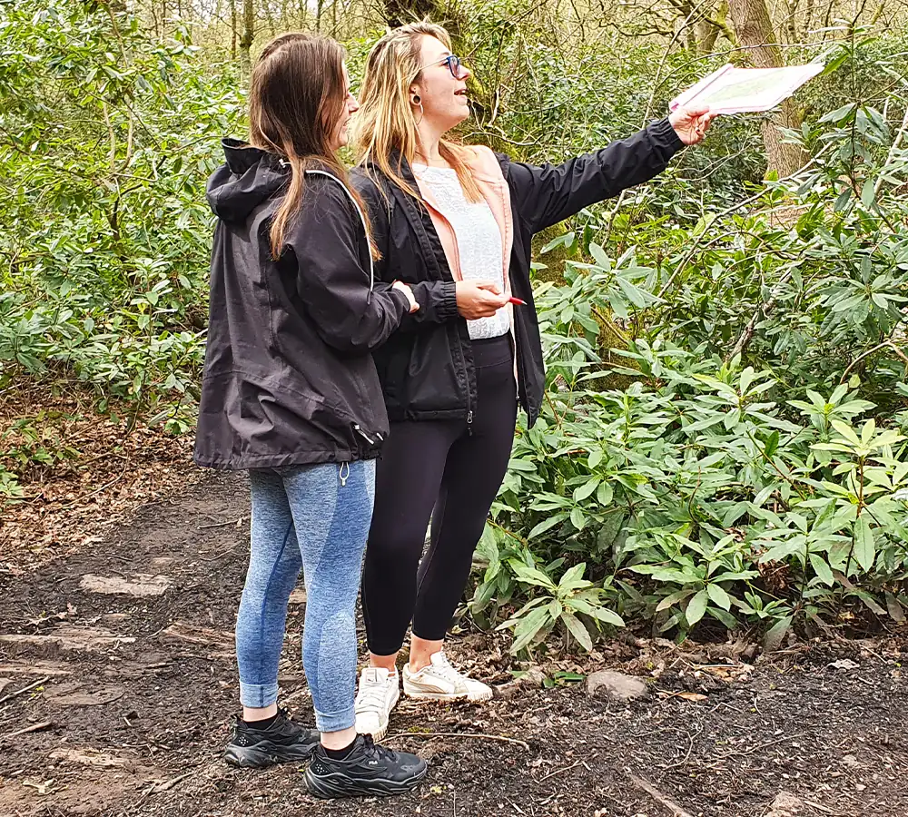 Two friends pointing, completing a woodland orienteering course in manchester