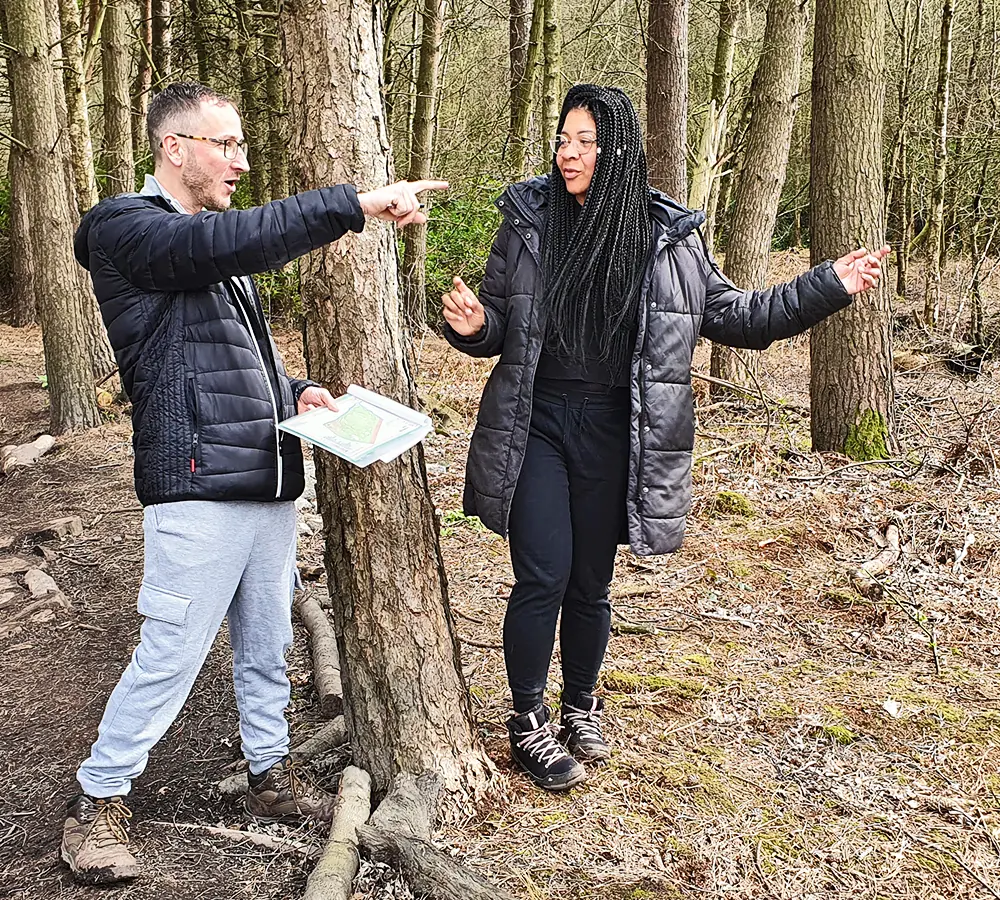 An excited couple with a map walking in the woodland