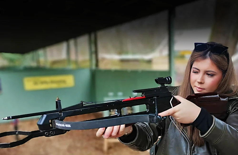 Smiling lady with sunglasses shooting a crossbow on a hen do