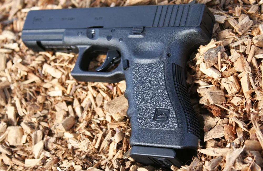 Closeup of a Glock 17 pistol on a woodchip background