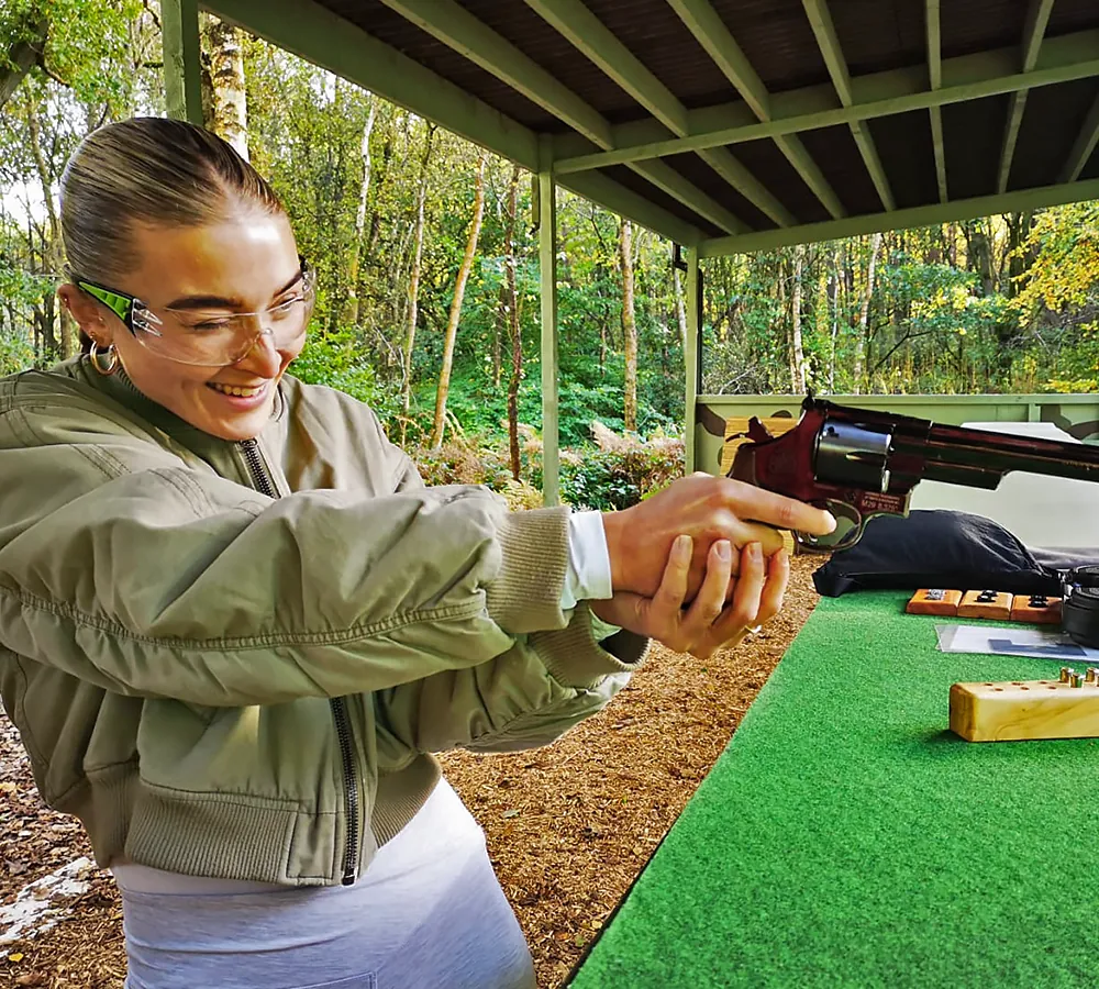 Happy girl wearing shooting glasses, shooting a Smith and Wesson six-shooter handgun