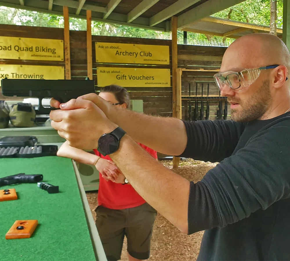 Concentrating guy firing a Glock 17 gun. Shooting instructor watching him shoot