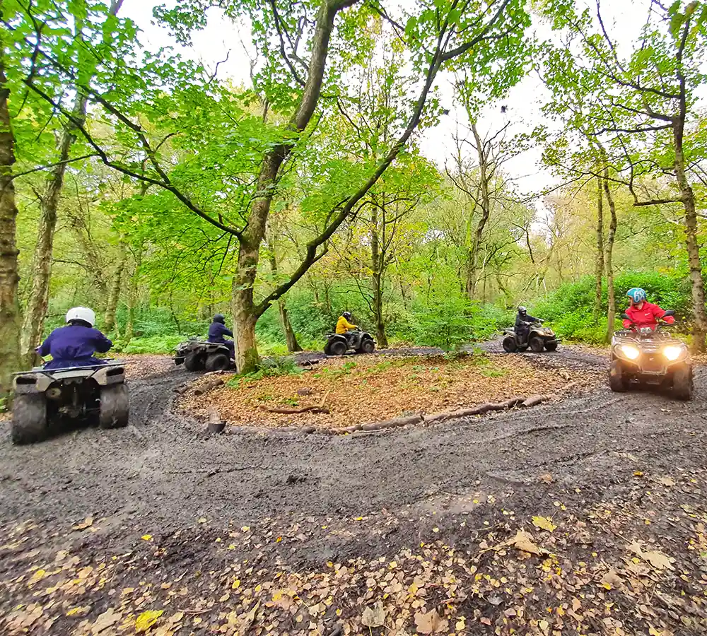 People driving quad bikes following an instructor around a training course