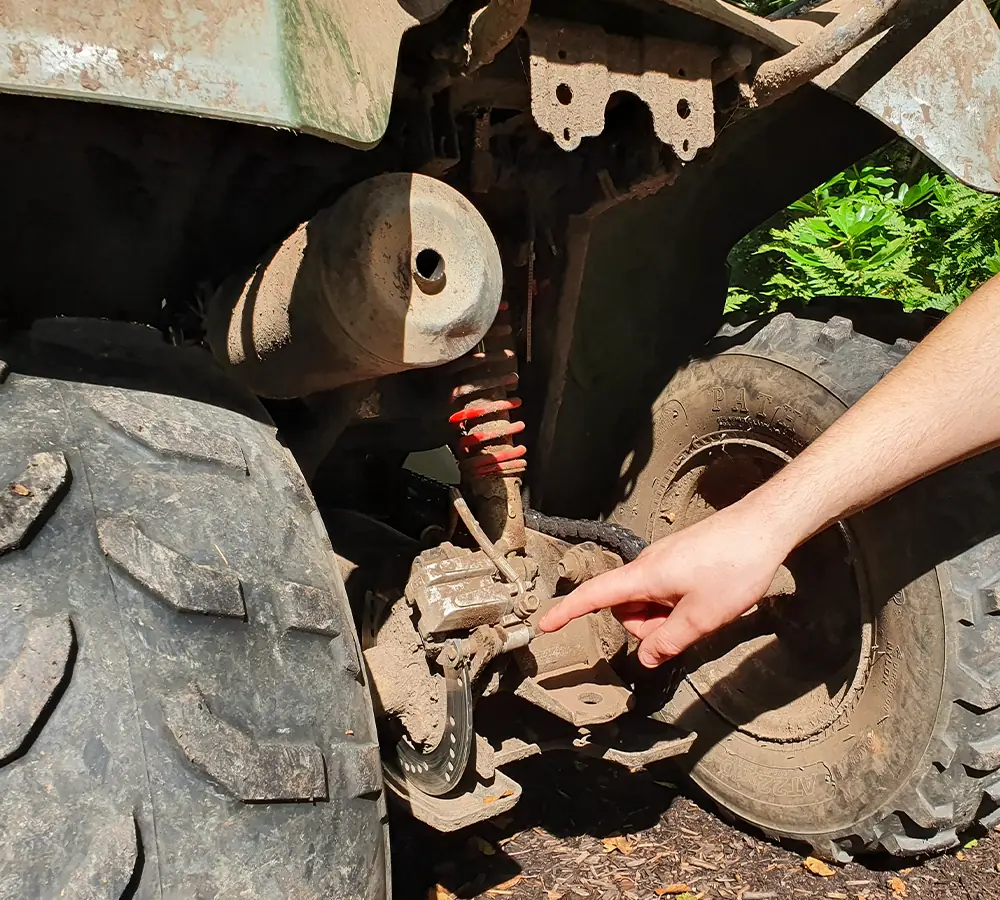 Quad bike maintenance explanation, pointing at rear disk brakes