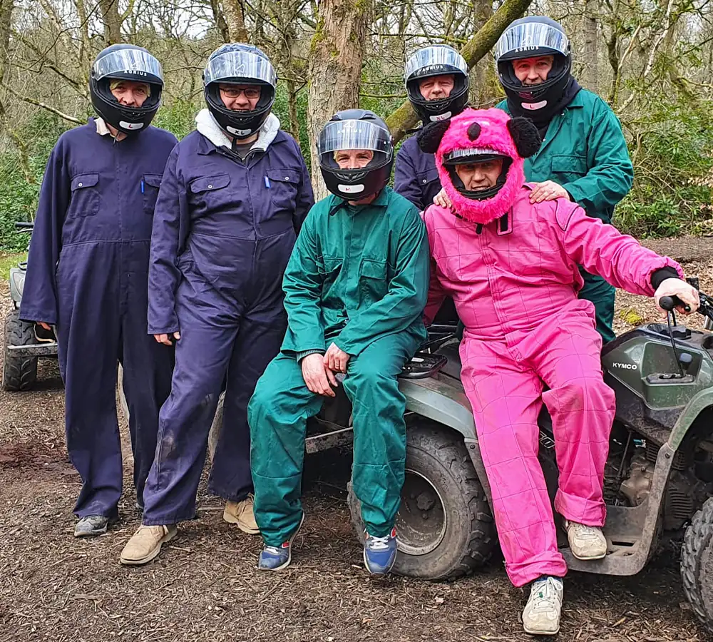 Group of 5 friends stood with quad bikes, dressed with overalls and helmets