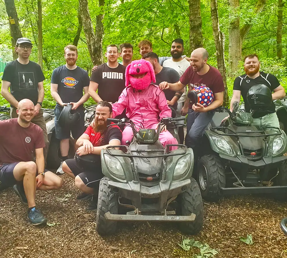 Large group of happy men stood and posing around quad bikes