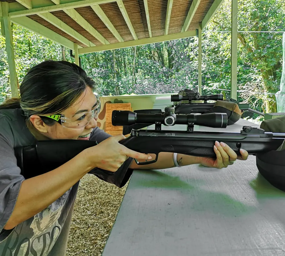 Smiling lady shooting at Adventure Now's air rifle range