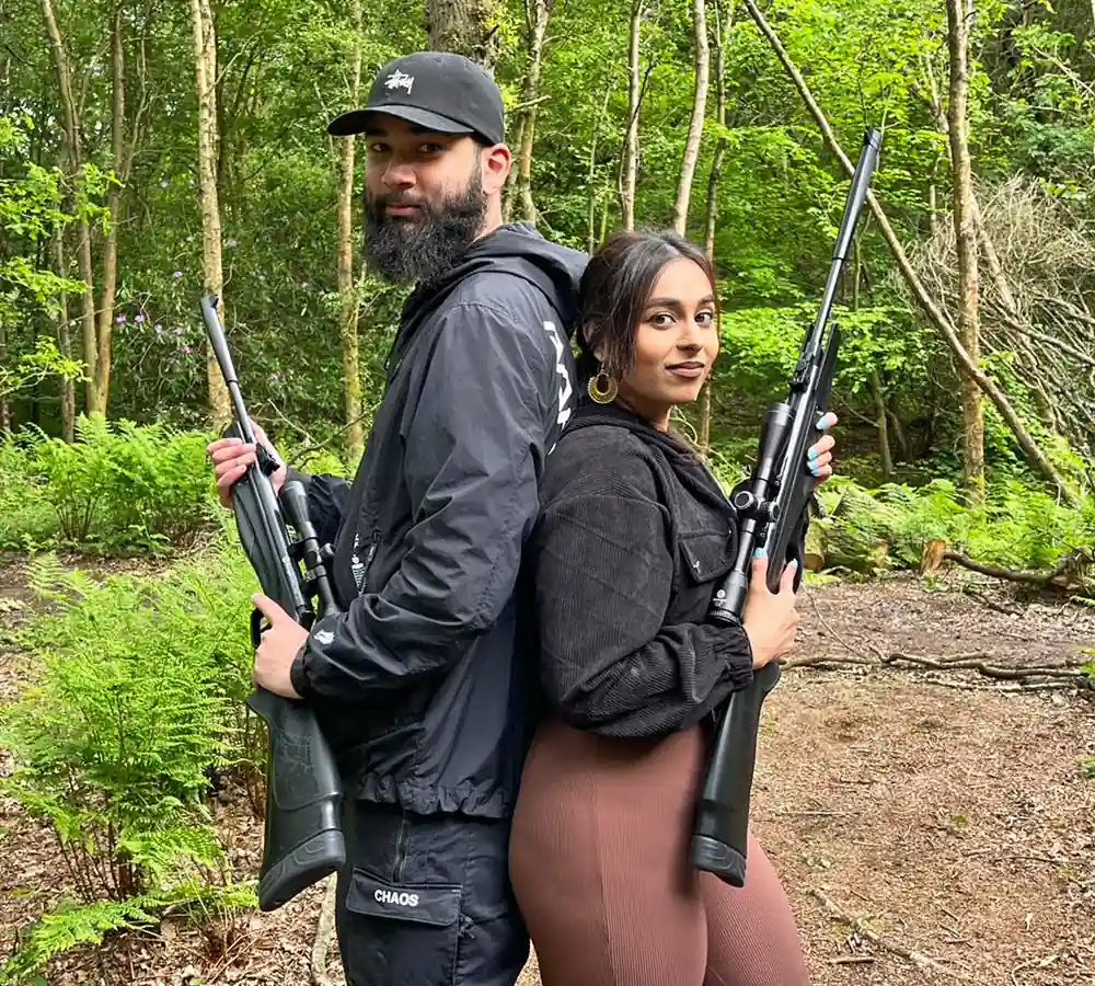 A fun, happy couple both posing together holding air rifles