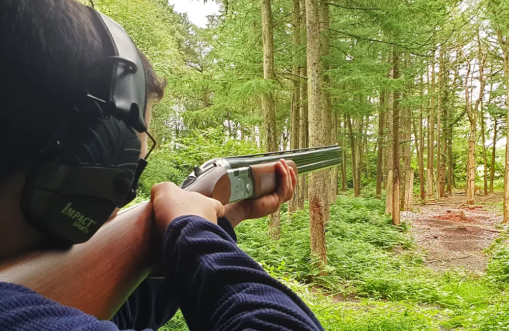 Person clay pigeon shooting, pointing a shotgun ready to shoot a flying clay at Adventure Now Manchester