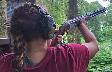 Lady shooting 12 gauge shotgun outdoors at Adventure Now Manchester