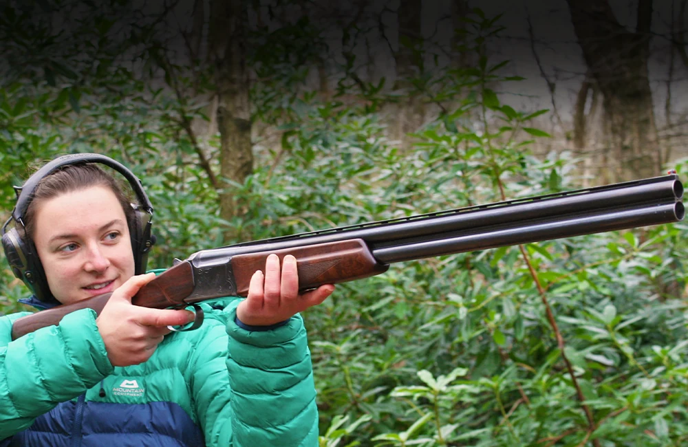 Lady holding and pointing a shotgun into the air ready to fire