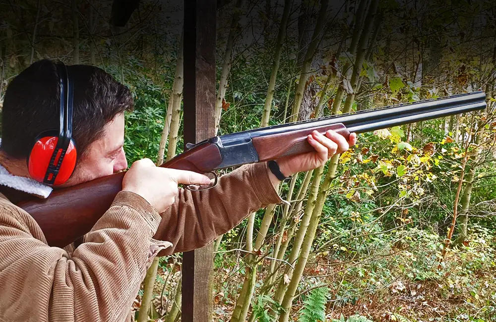 Man holding and pointing a shotgun into the air ready to fire