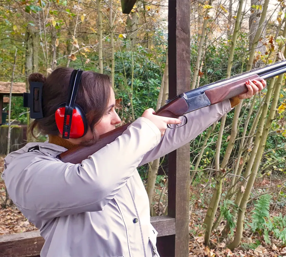 Happy lady clay pigeon shooting in a shooting stand at Adventure Now Manchester