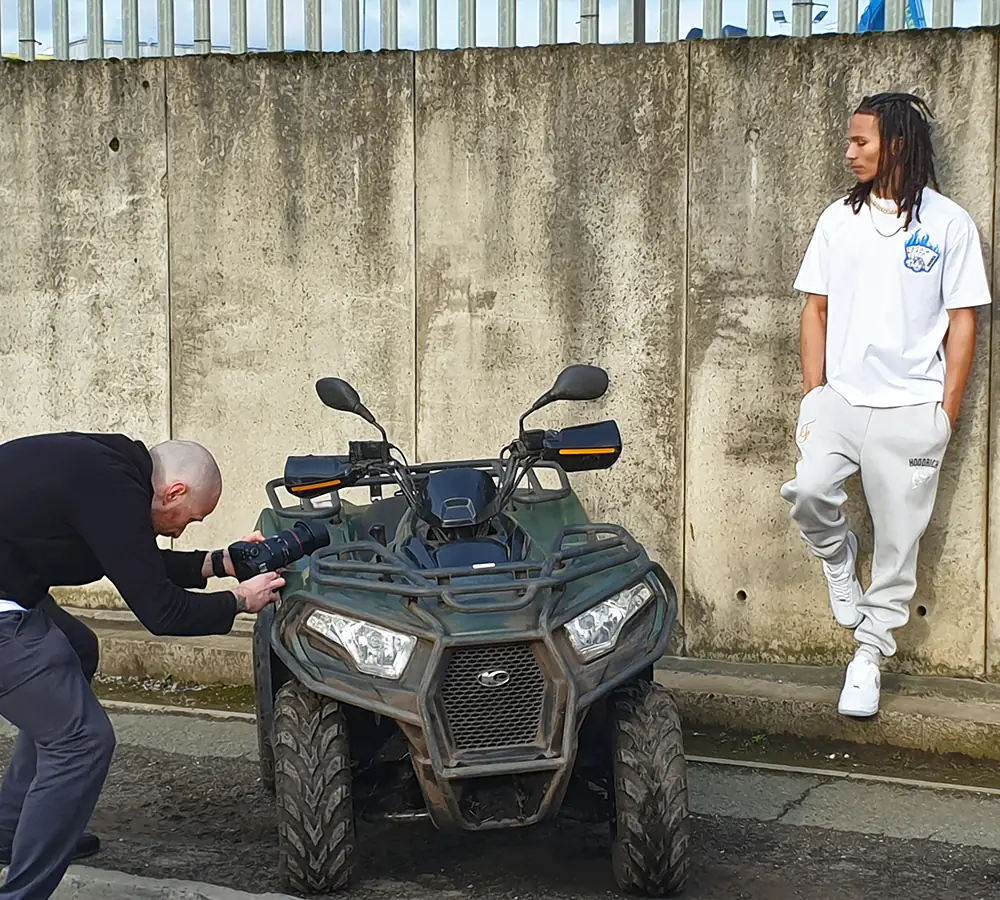 Photographer taking a photo of a fashion model with a quad bike in an urban film shoot