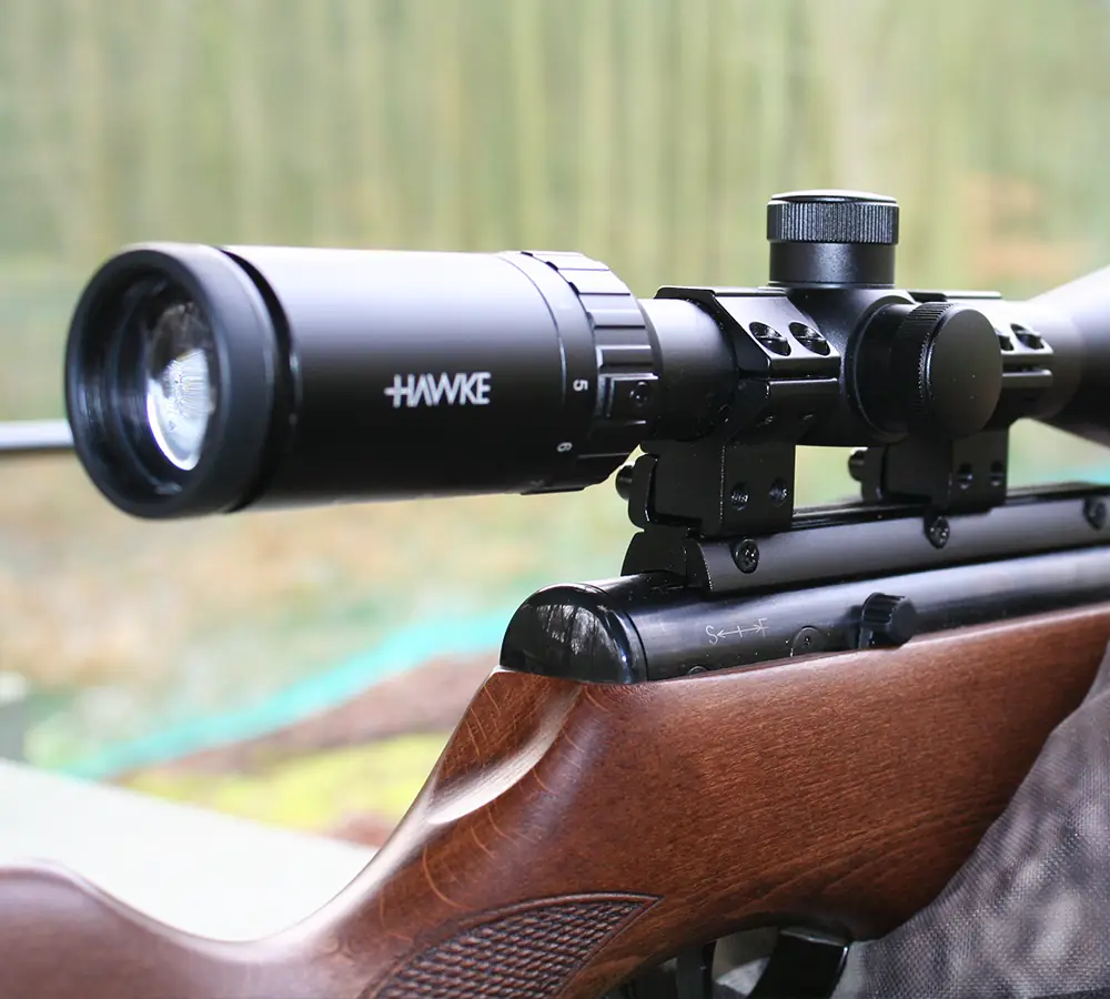 Closeup photo of a rifle with a wooden stock and telescopic scope