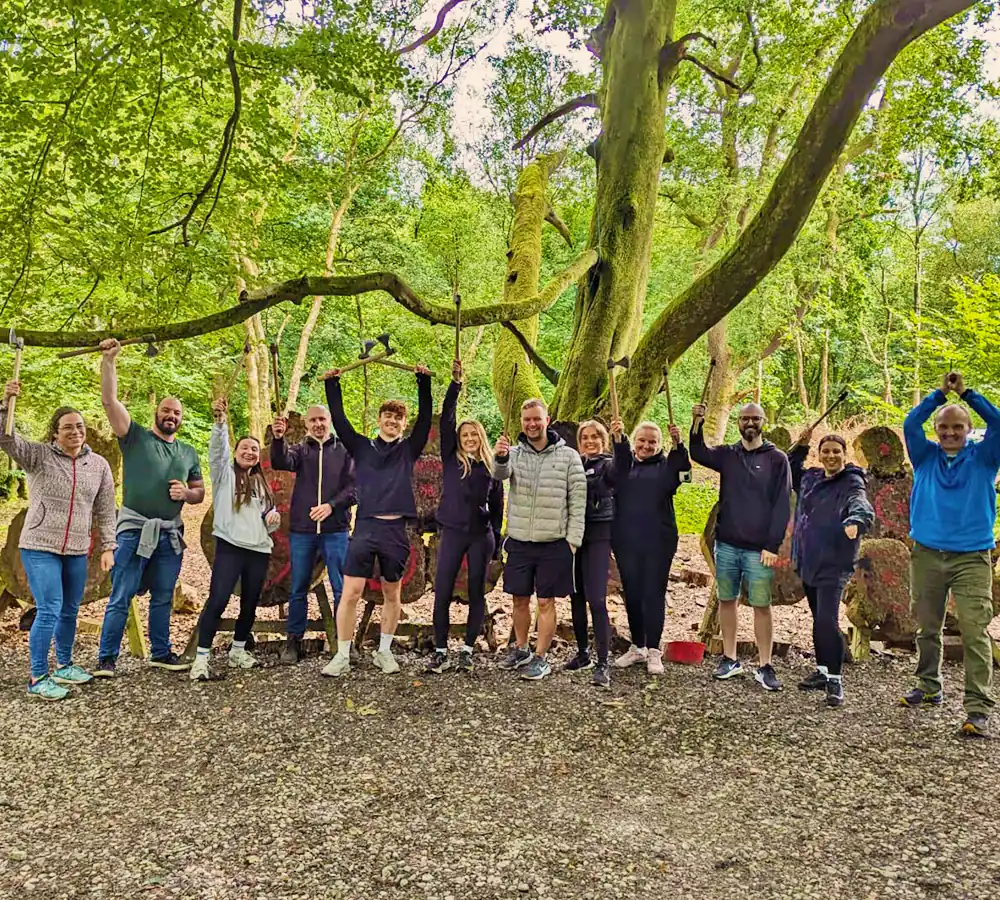 Excited company group doing axe throwing, holding throwing axes up in the air