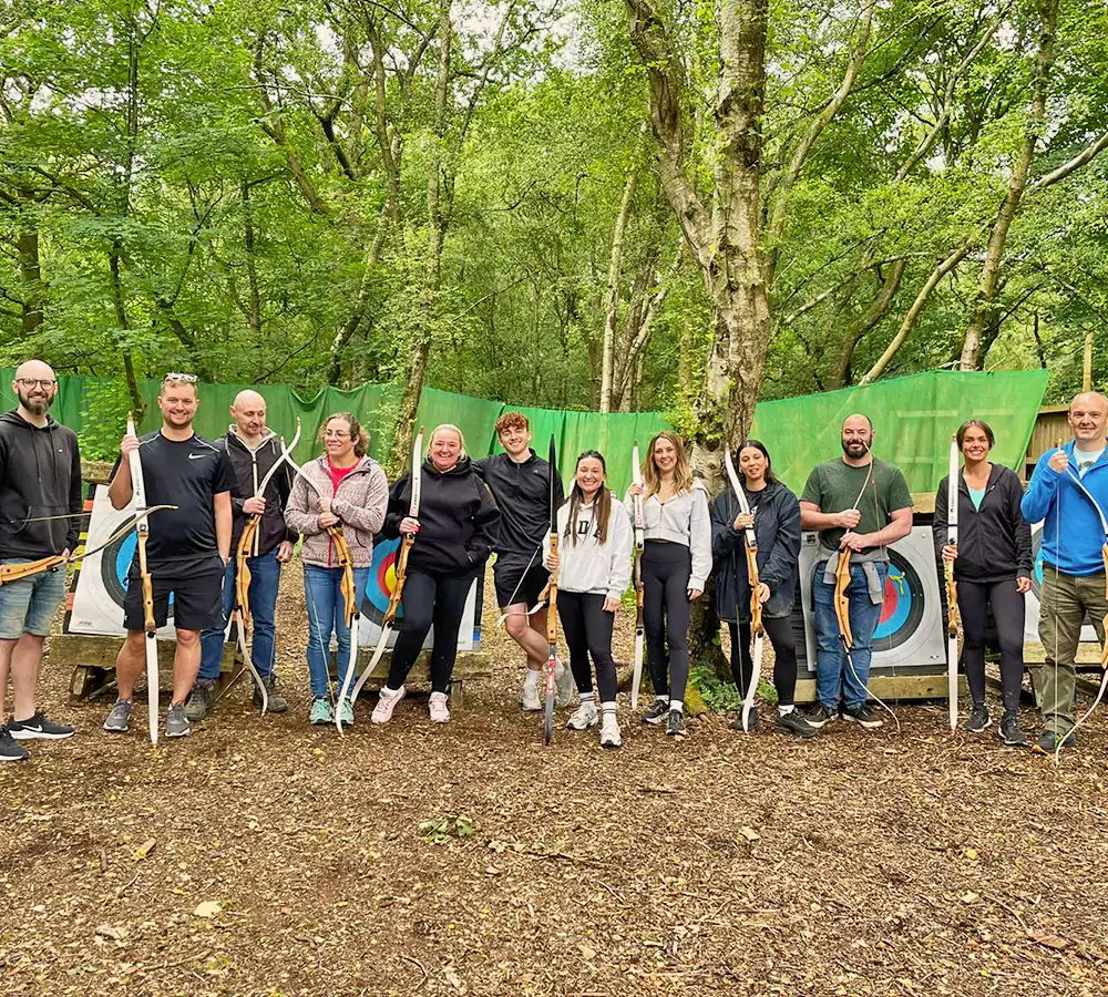 Large team of people together with archery bows and targets outdoors