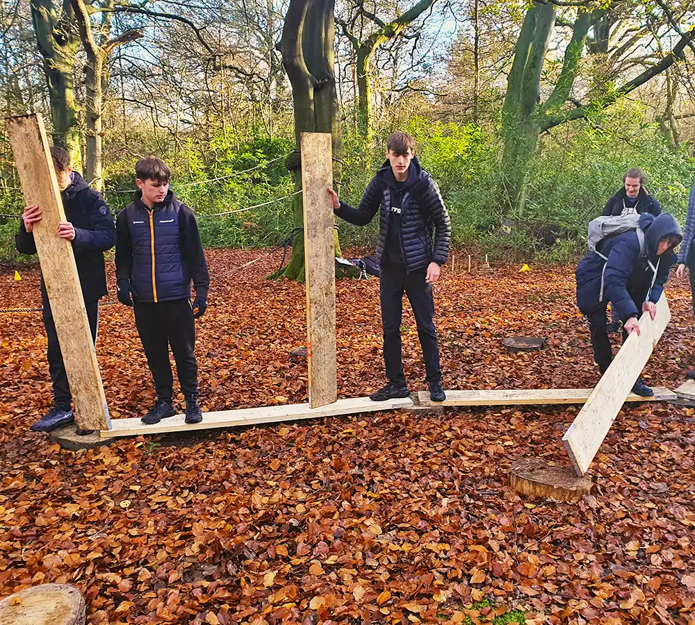 Team building game involving creating a bridge using scaffolding planks at Adventure Now Manchester