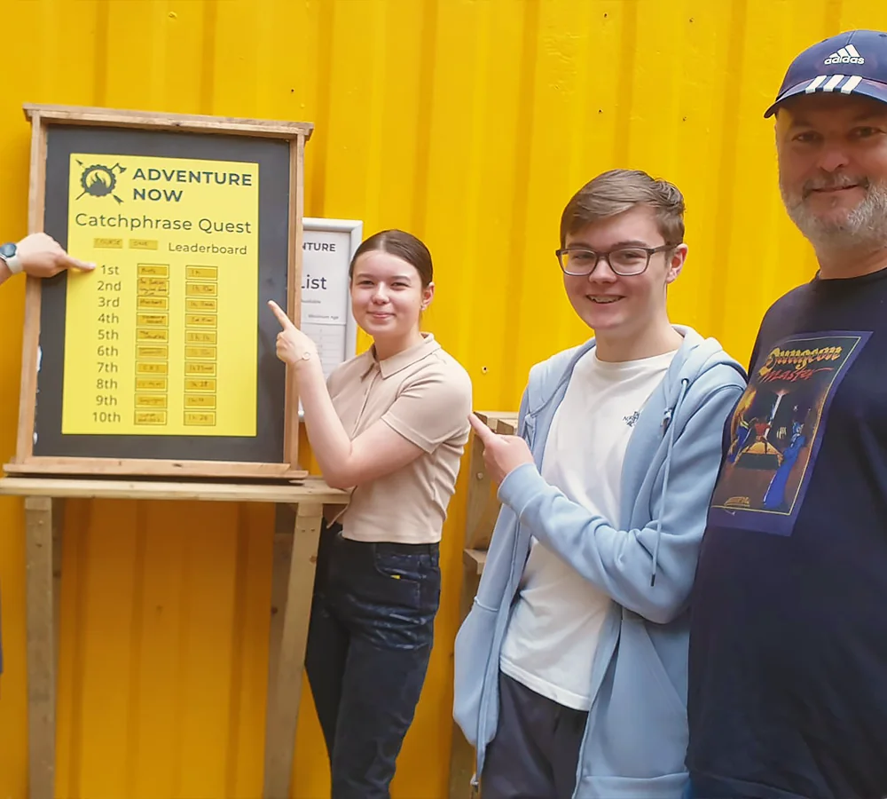 Family group pointing to their place on the woodland orienteering leaderboard at Adventure Now