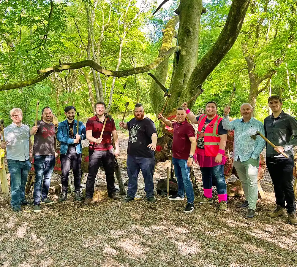 Group of friends together doing axe throwing, stood in front of throwing axe targets