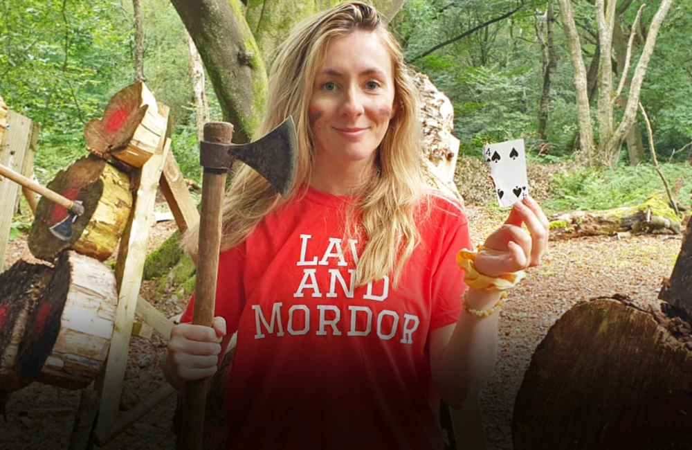 Blonde lady on a hen do smiling and holding a throwing axe at Adventure Now