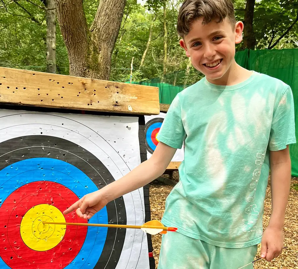 Birthday boy pointing at an arrow he shot into the yellow bullseye at his party at Adventure Now