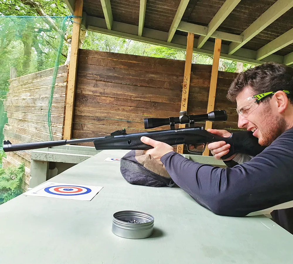 Man shooting an air rifle as part of a stag do at Adventure Now in Manchester