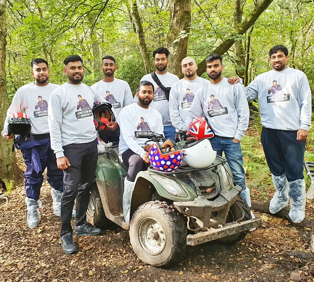 Large group of men around a quad bike with the groom sat on a quad bike. Everyone is wearing matching shirts