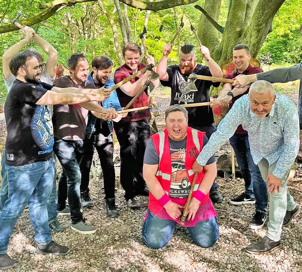 Stag do doing axe throwing. The group are holding axes around the stag in the middle