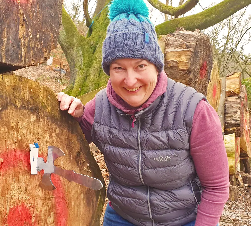 Smiling lady stood with wooden target with a throwing knife stuck into it