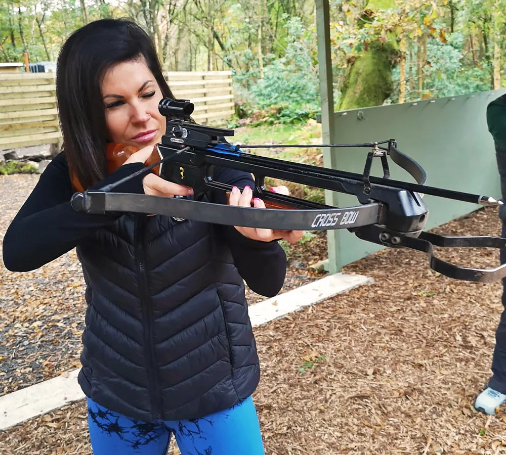 Smiling lady shooting a crossbow for the first time at Adventure Now in Manchester