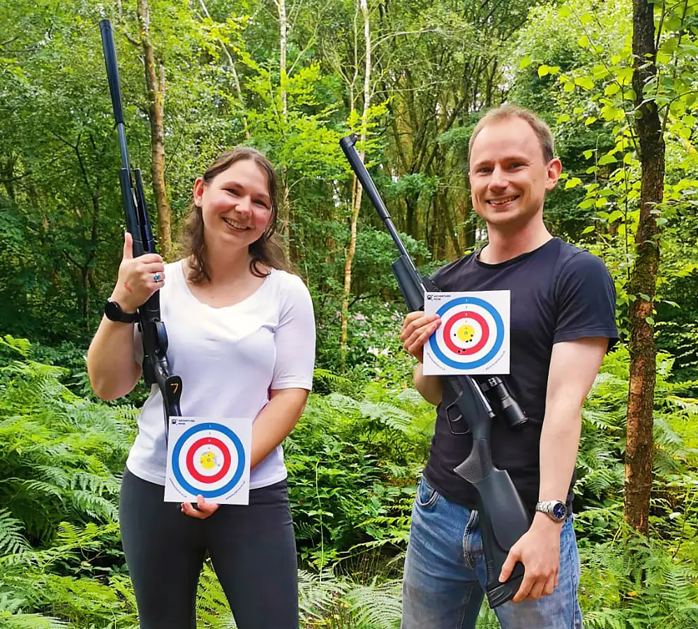 Happy couple posing with air rifles and score cards after shooting the rifles