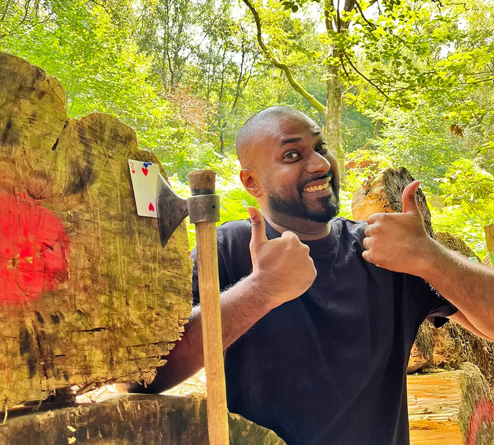 Excited man with a throwing axe stuck in a target at Adventure Now Manchester