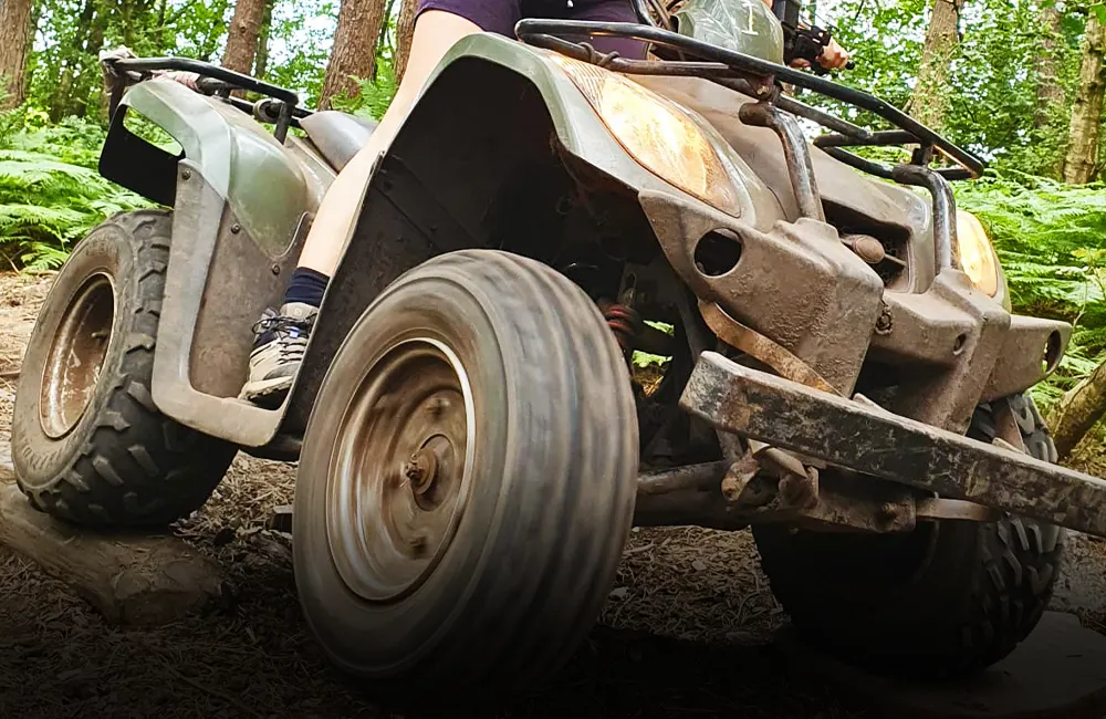 Action shot of a Quad Bike driving in a sunny woodland in manchester