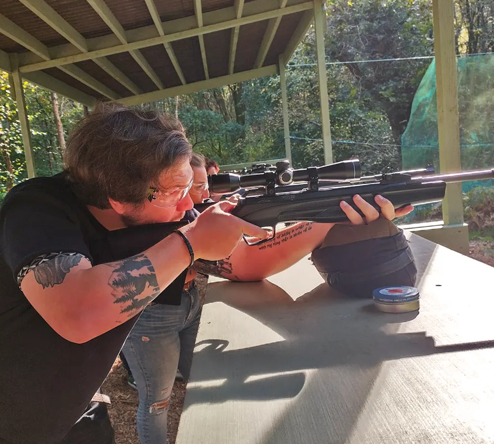 Group of people shooting air rifles with telescopic sights in an outdoor shooting range