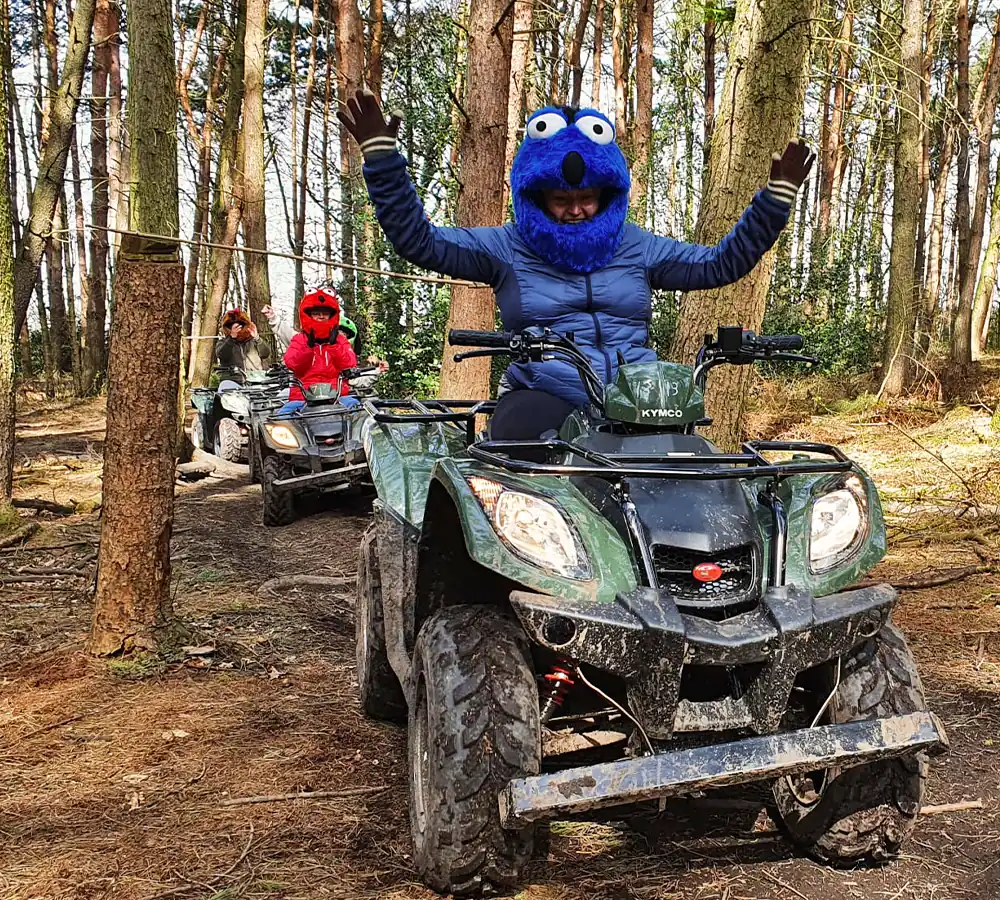 Excited lady riding an ATV with her hands up in the air